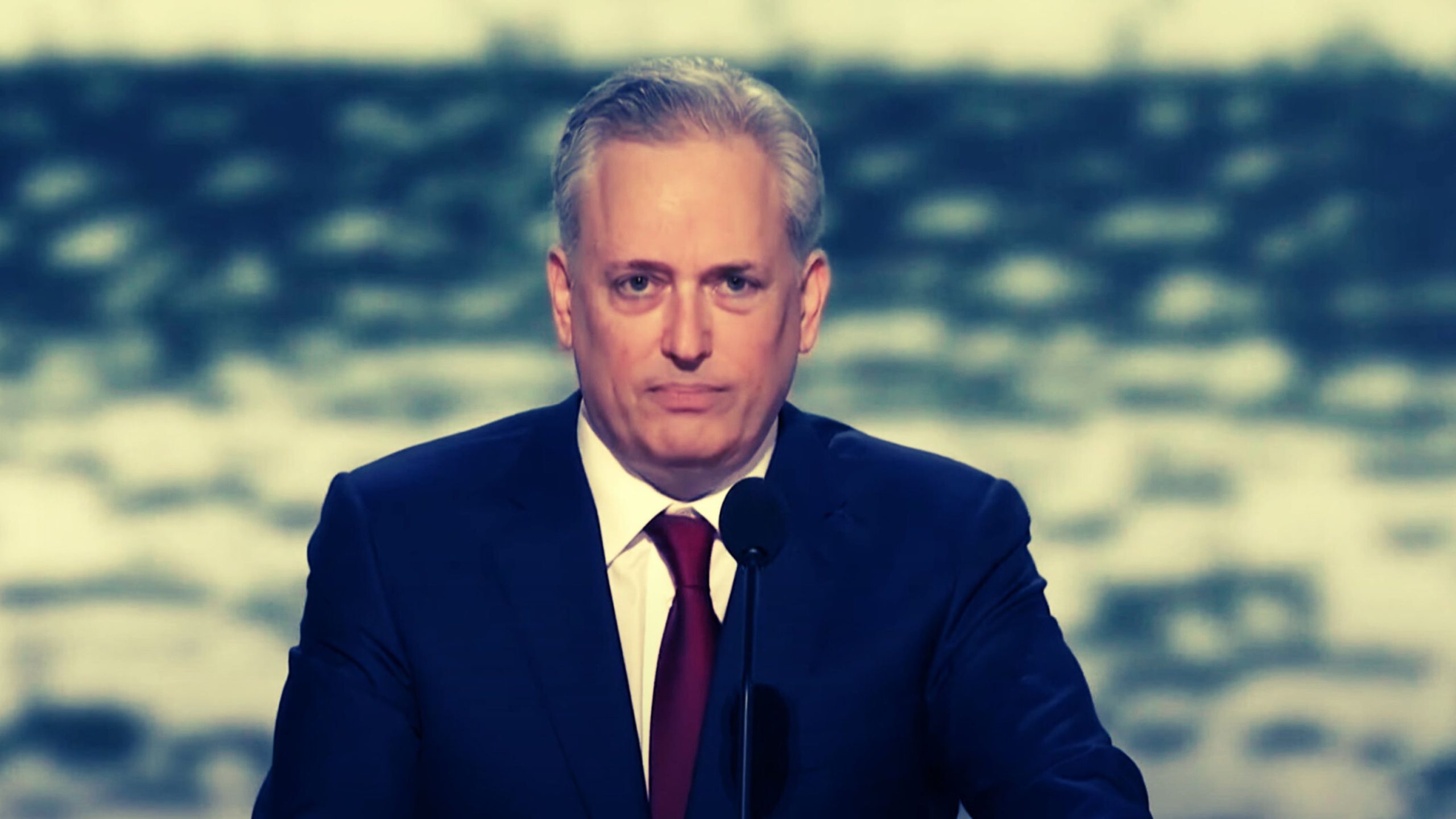 David Sacks in a suit speaking at a microphone.