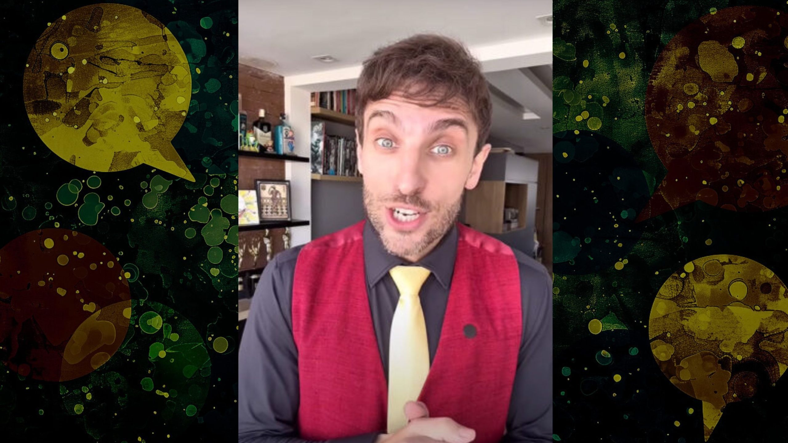 Leo Lins comedian with short brown hair, wearing a red vest over a black shirt and a yellow tie, speaking indoors with shelves and various items in the background.