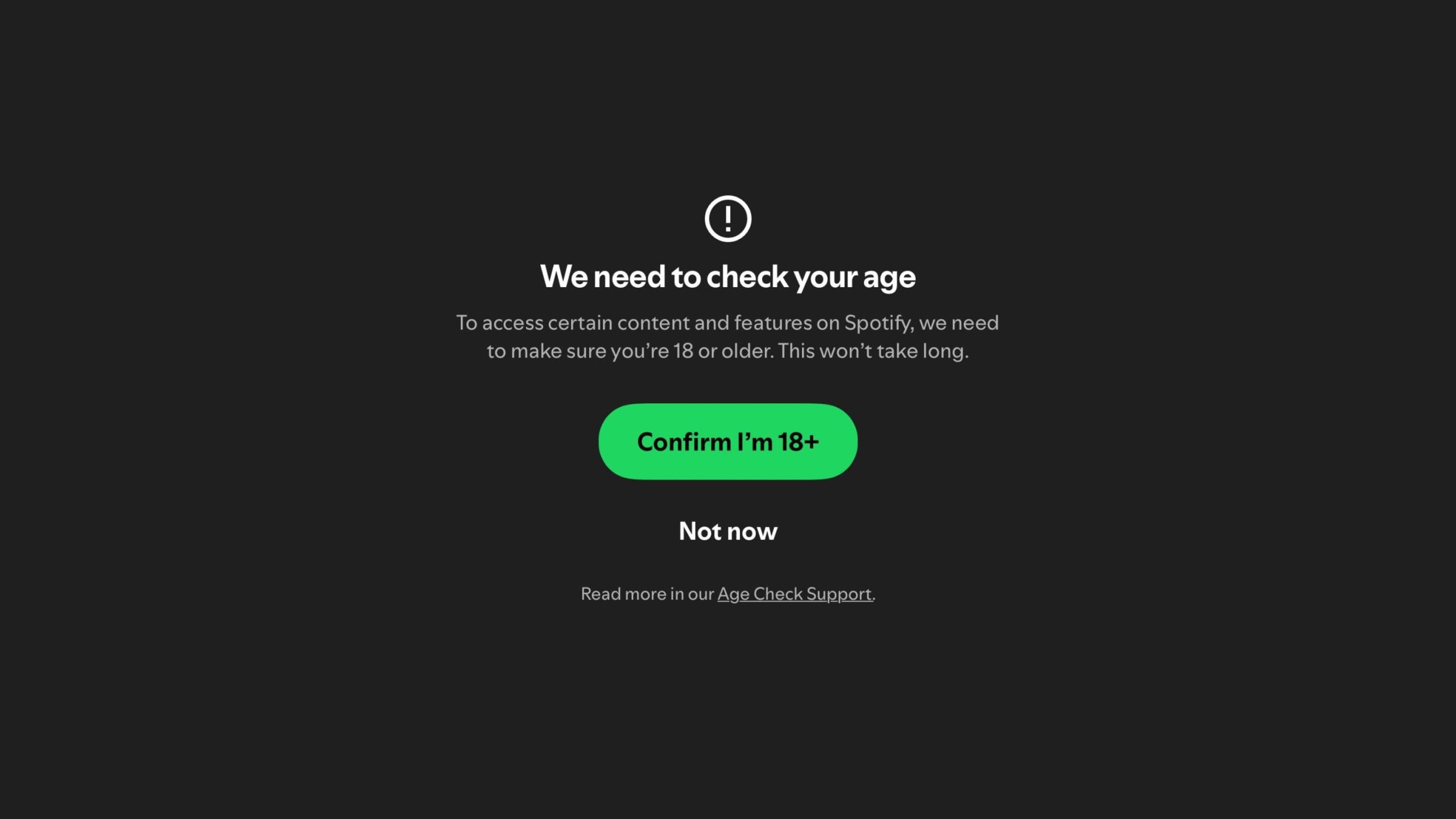 Age verification prompt on a dark background with a warning icon, asking to confirm if the user is 18 or older to access content on Spotify, featuring a green button that says "Confirm I'm 18+" and an option below labeled "Not now" along with a link to Age Check Support.