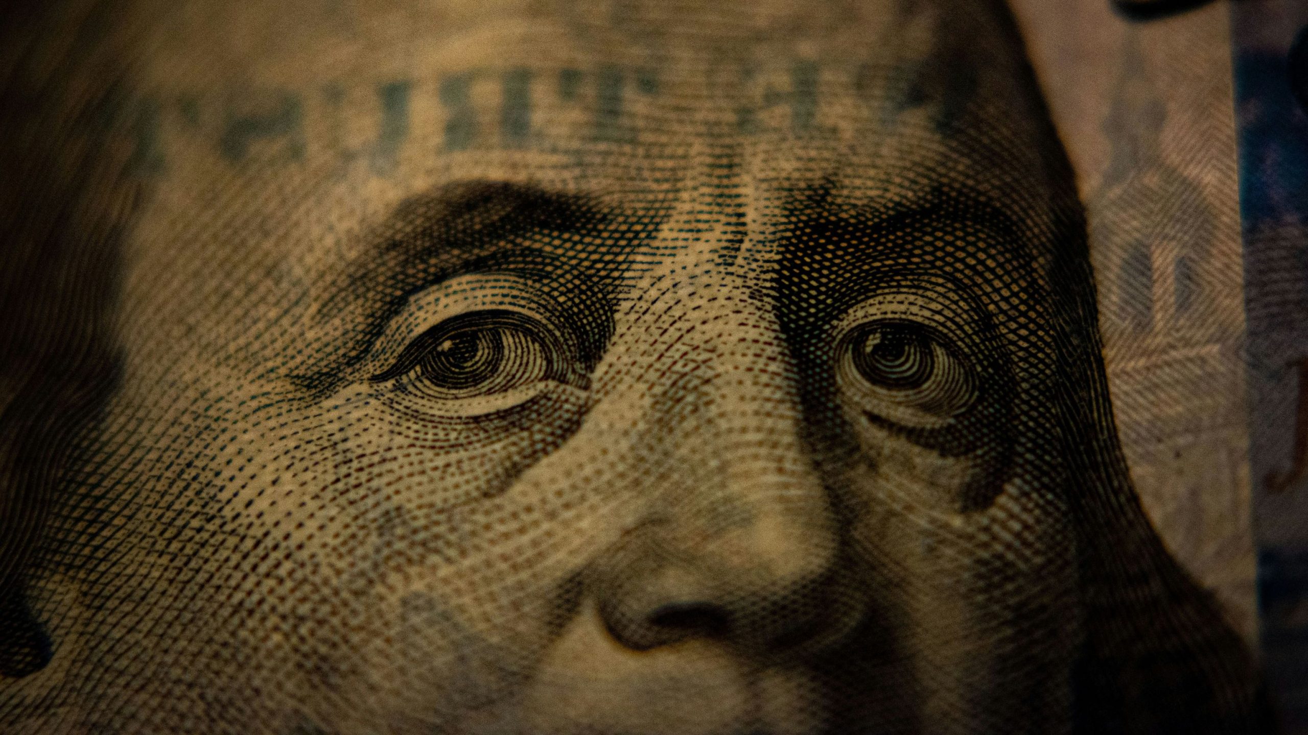 Close-up of Benjamin Franklin's eyes and nose on a U.S. one hundred dollar bill showing intricate engraving details.