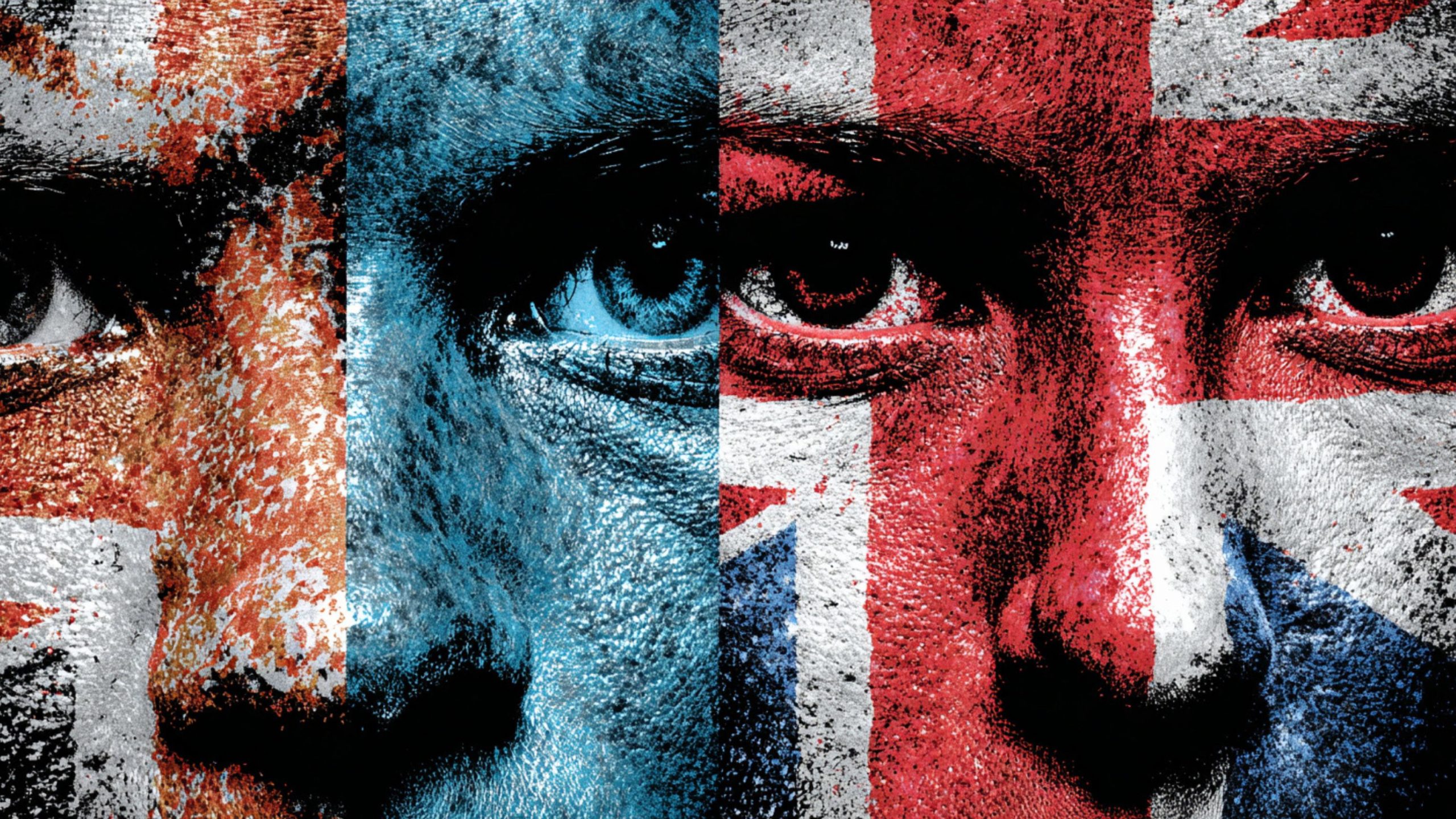 Close-up of a face divided into vertical panels painted with textured red, white and blue flag motifs (including Union Jack elements), emphasizing intense eyes and cracked, weathered skin.