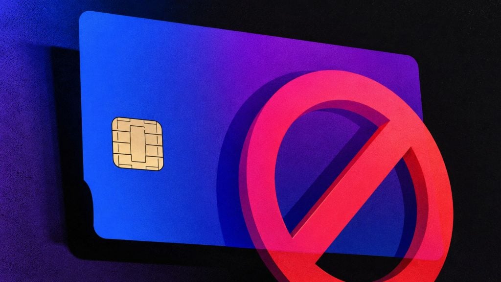 Blue credit card with visible gold chip partially obscured by a red prohibition symbol on a dark background