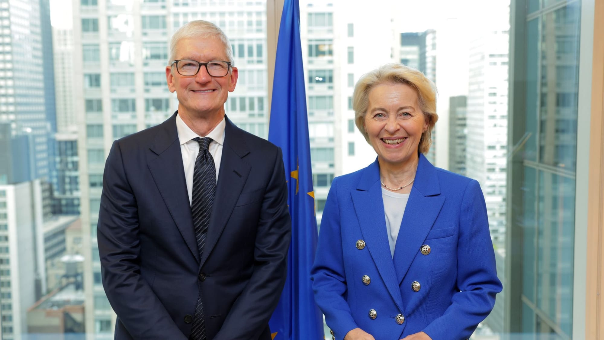 Apple CEO Tim Cook and European Commission President Ursula von der Leyen smile together in front of an EU flag.