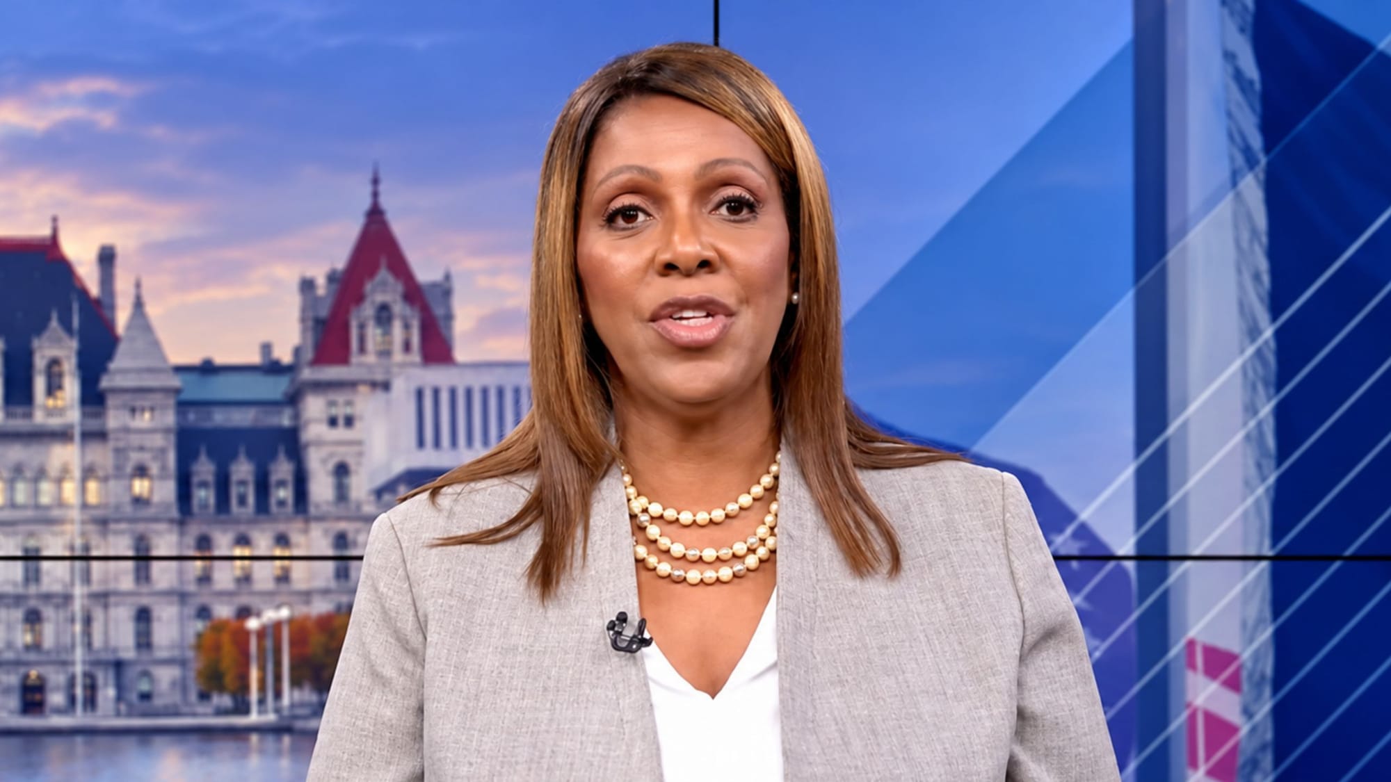 New York Attorney General Letitia James speaking in front of a backdrop featuring the New York State Capitol.